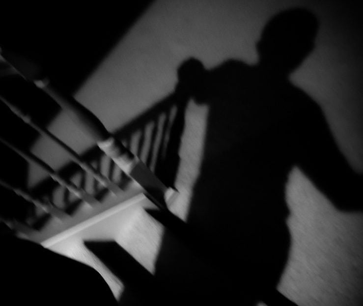 The shadow of a human-like figure on a staircase in the dark