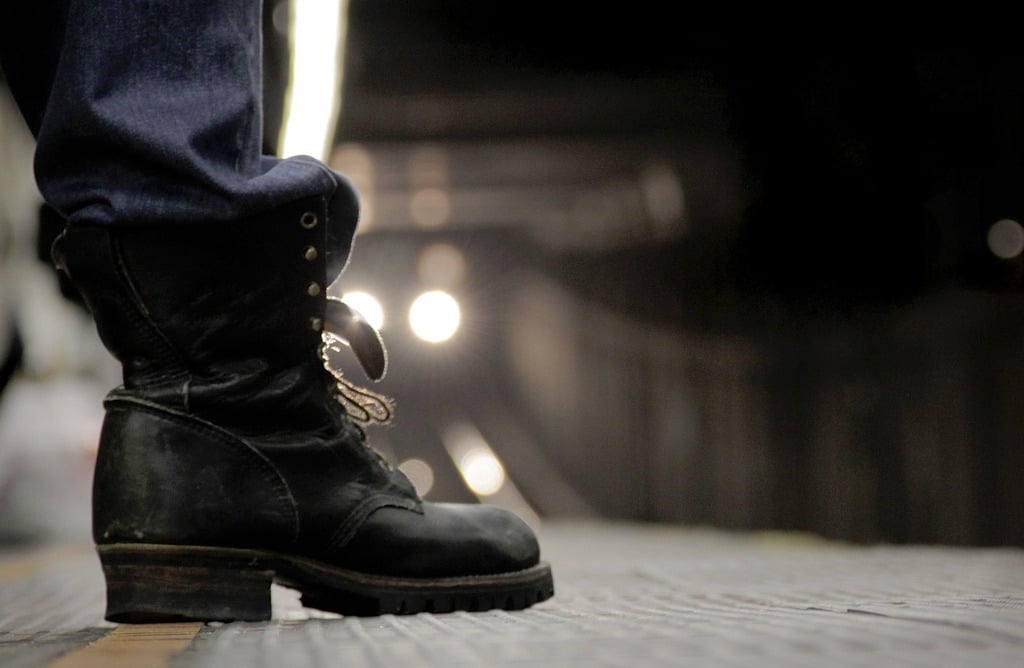 A person wearing boots standing on a subway platform