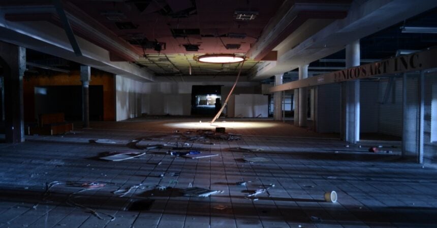 the interior of a dead shopping mall, dark, abandoned, and falling apart