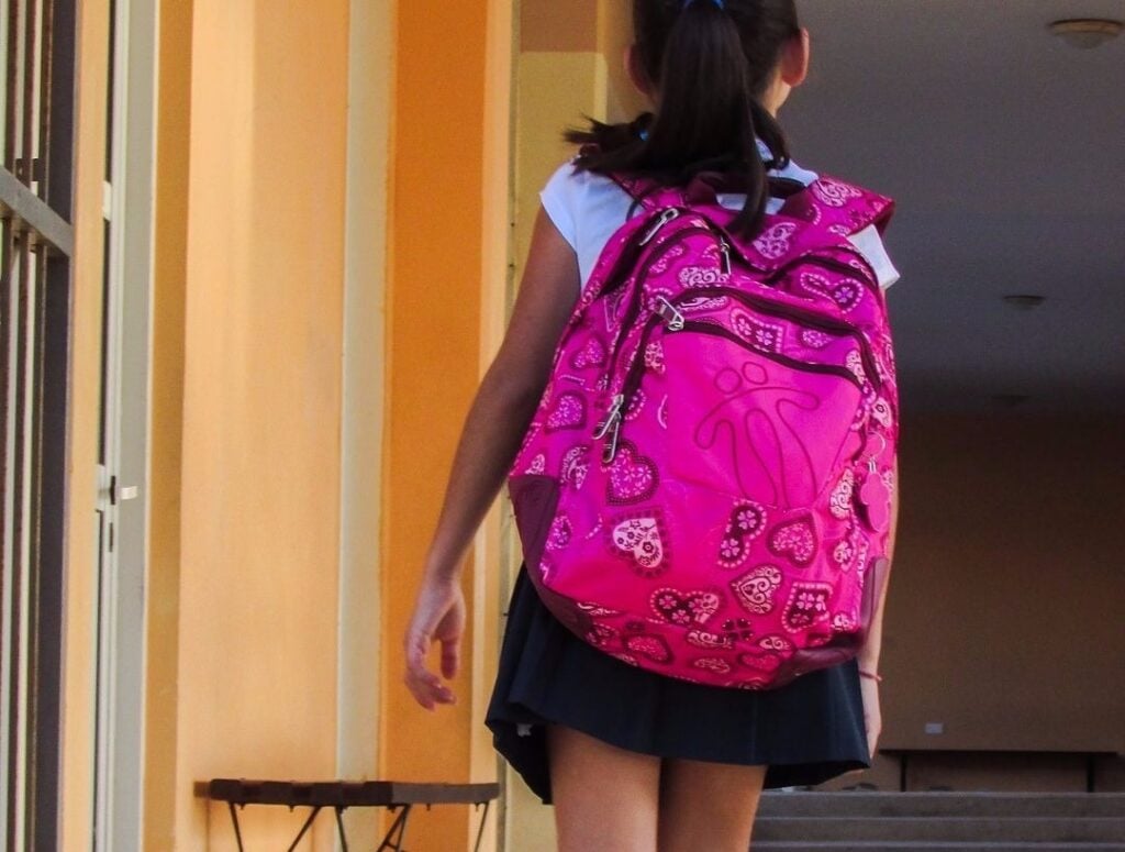 A child wearing a pink backpack