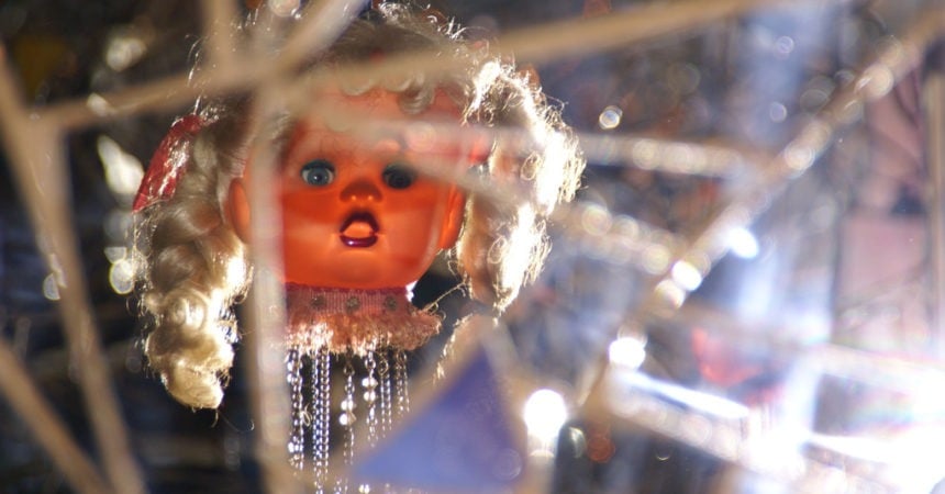 A doll head reflected in a cracked mirror