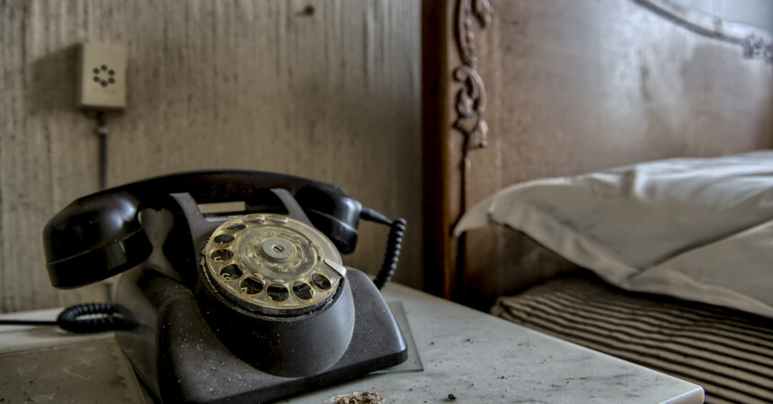a rotary phone sitting beside a bed in an abandoned bedroom