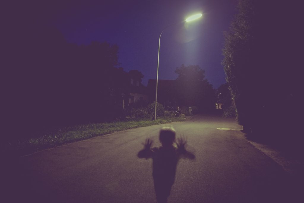 A child's silhouette on a street at night