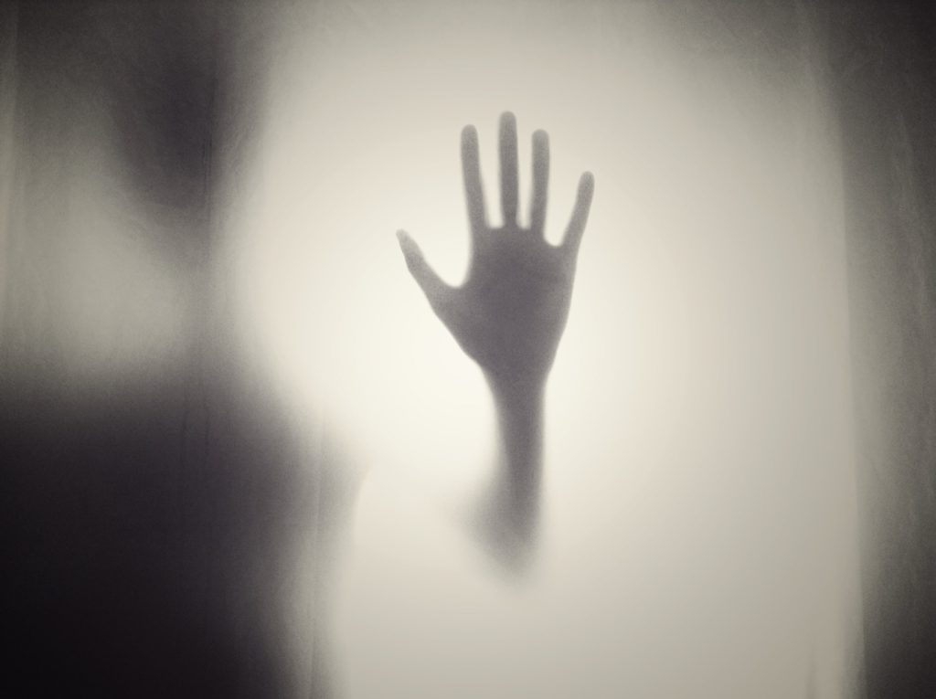 Silhouette of a hand viewed through a curtain