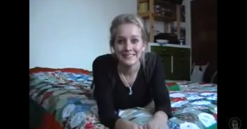 A blonde, white, female-presenting person - Louise Paxton - lying on a bed, facing the camera