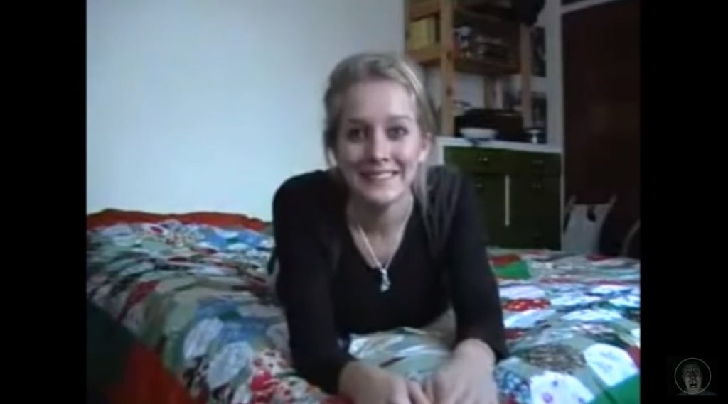 A blonde, white, female-presenting person - Louise Paxton - lying on a bed, facing the camera