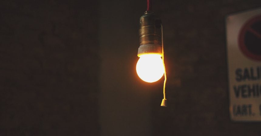 a bare lightbulb lit in an otherwise dark room