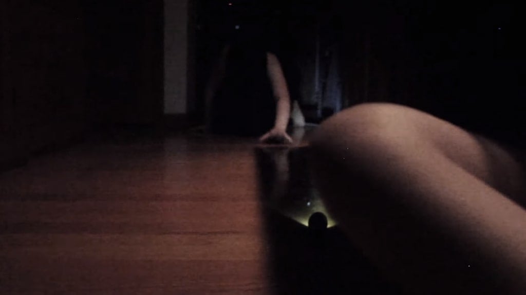 Screenshot from Hi I'm Mary Mary showing the woman in black crawling towards Mary in the dark