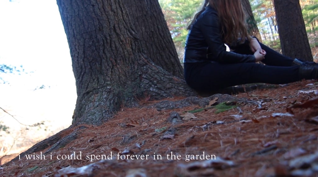 Screenshot from Hi I'm Mary Mary showing Mary on the ground by a tree in the garden