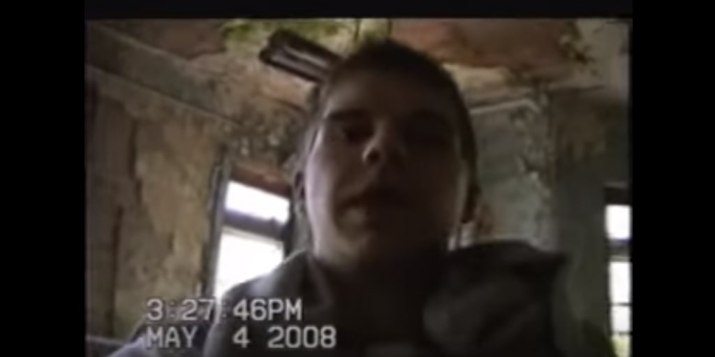 A closeup of the face of a male-presenting person in a building at the abandoned ruins of the Pennhurst State School and Hospital