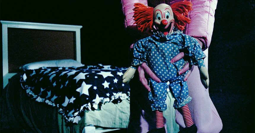 A child in a bedroom with a clown doll