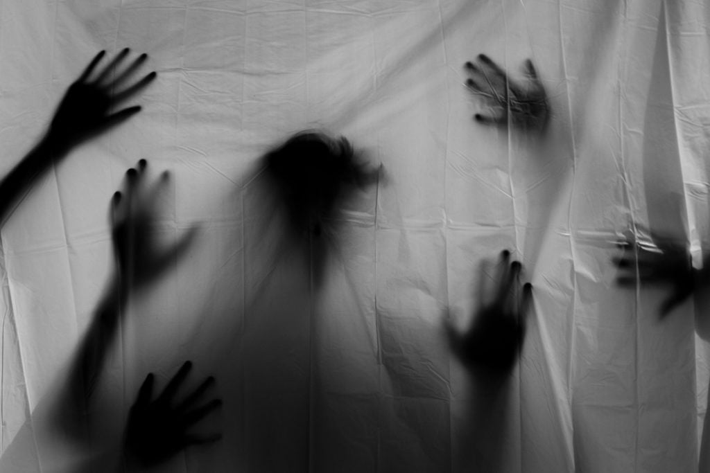 Shadowy hands pressed against a cloth, lit from behind