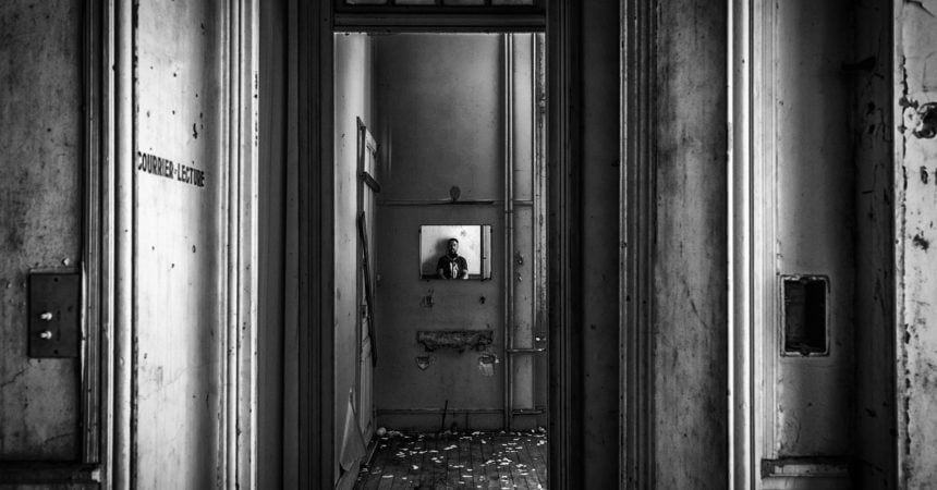 A person reflected in a mirror in an abandoned hallway