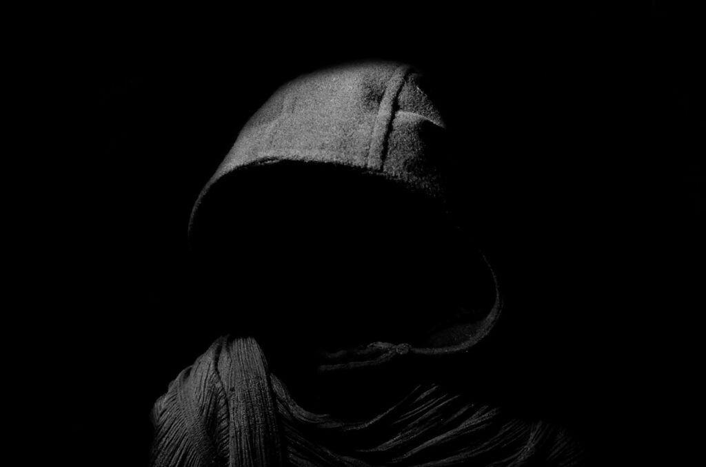 A hooded figure in the darkness