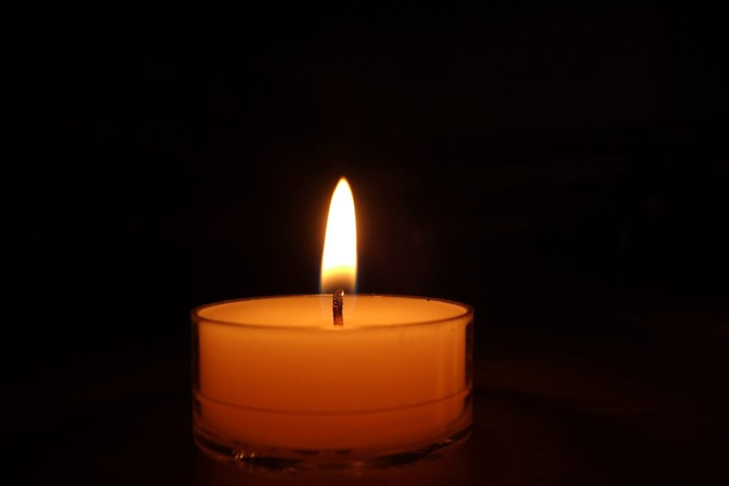 An orange candle lit in a dark room