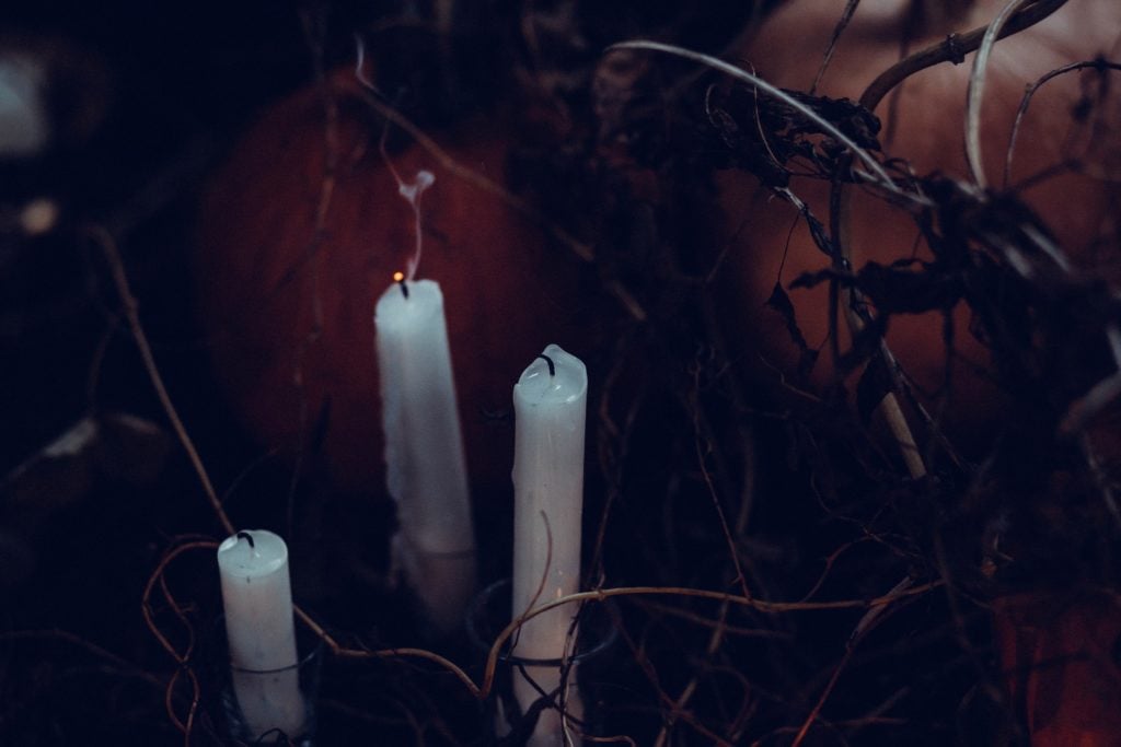White pillar candles in a dark and spooky environment