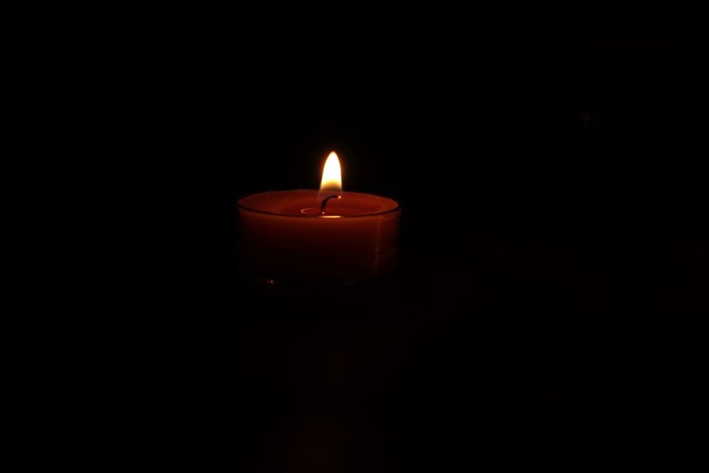 A red candle lit in a dark room