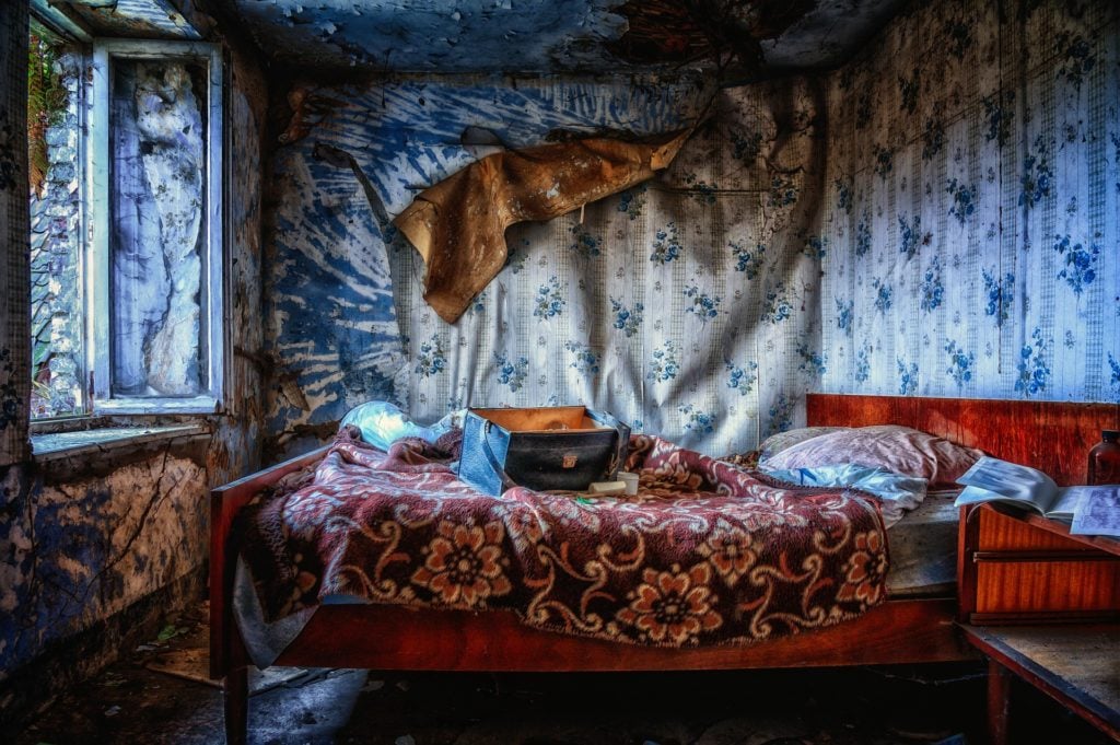 A bed in a decaying room