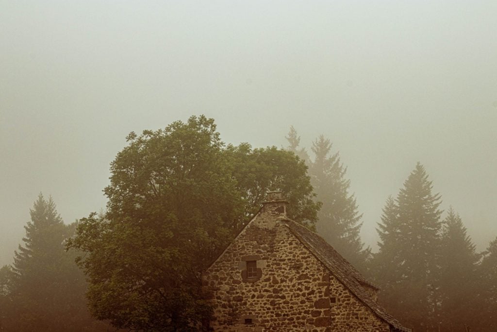 The roof of an old stone building in a foggy landscape