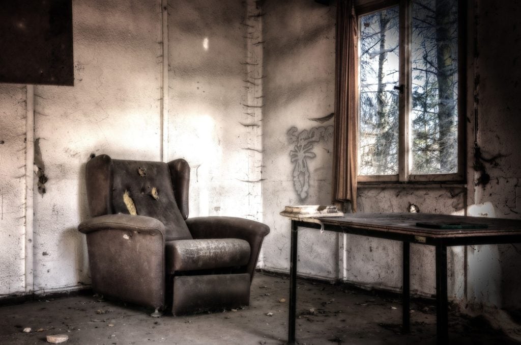 An old armchair and table in an abandoned room