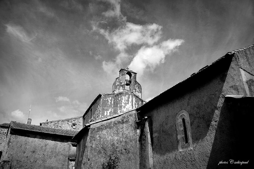 The spire and bell of the church in Celles, France rendered in black and white.