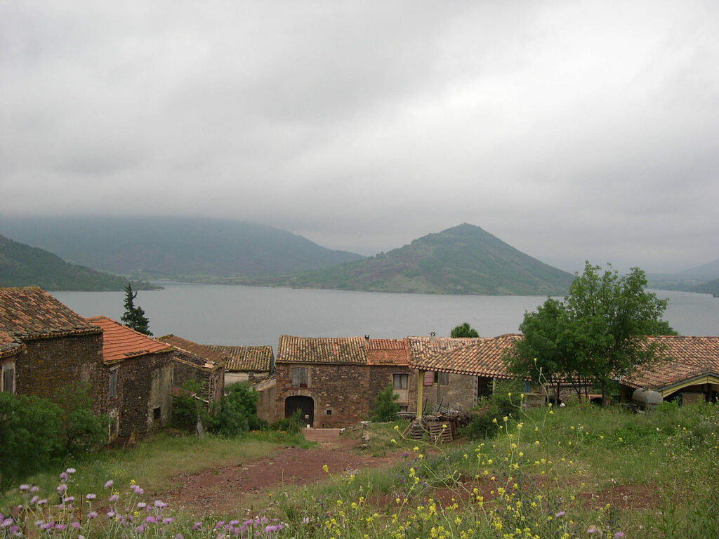 The remains of Celles, France with Lac du Salagou behind it on a foggy day.