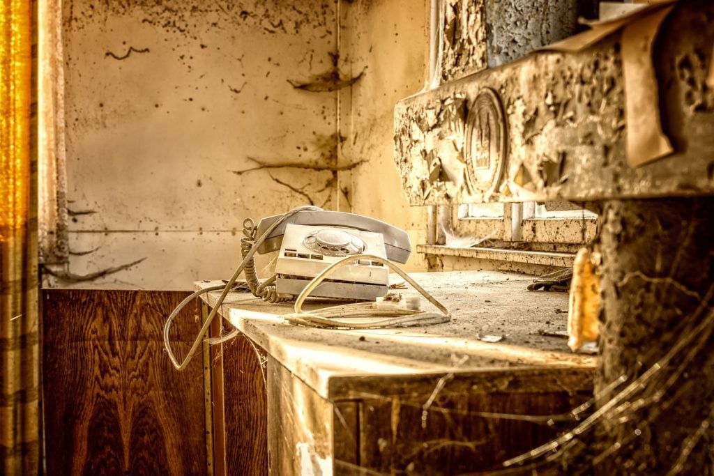 A dirty white phone on an abandoned desk