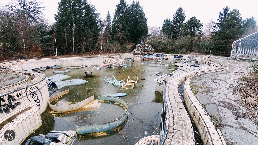 An empty, abandoned, outdoor pool with fake rocks and graffiti at the abandoned Blub water park in Berlin, 2015.