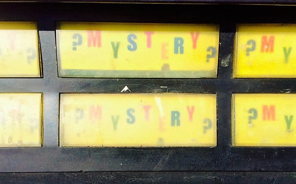 A close-up of Seattle's "mystery soda machine's" buttons: They are yellow and read "?MYSTERY?" in multi-colored letters.