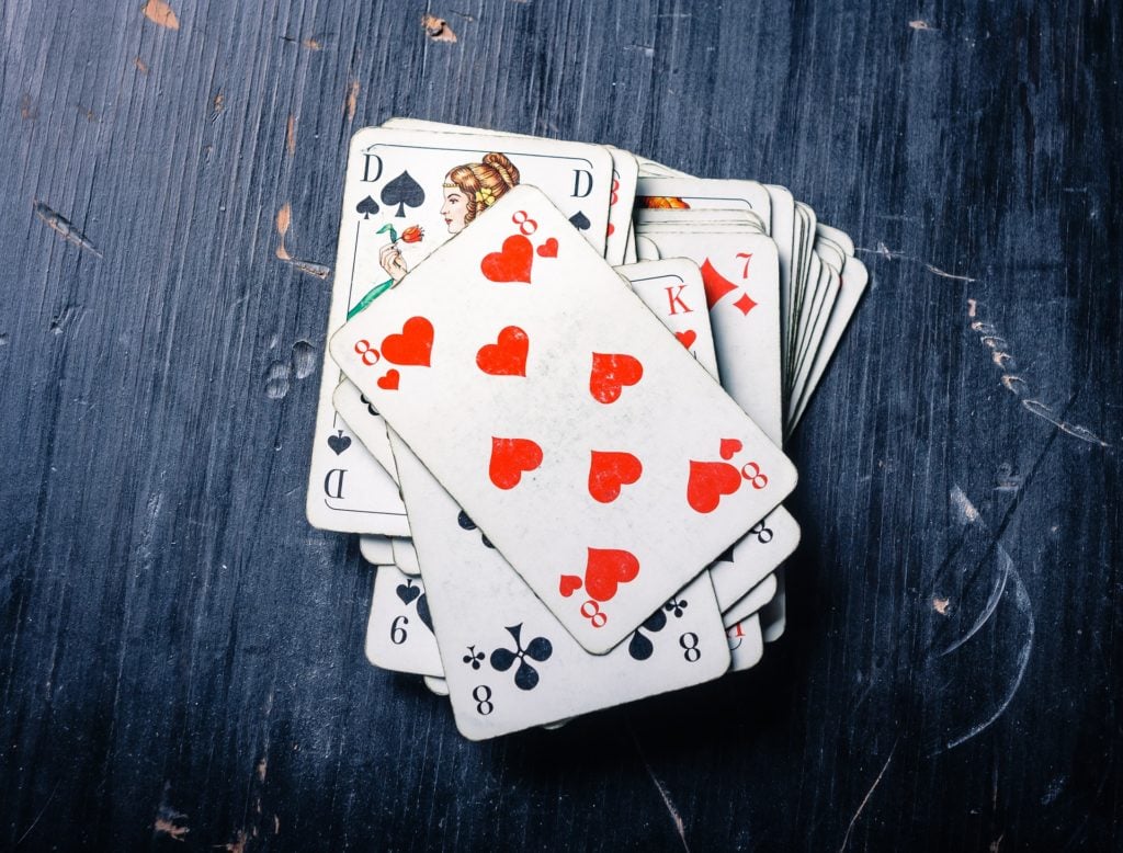 A pile of playing cards, face up on a scratched, blue-painted, wooden surface.