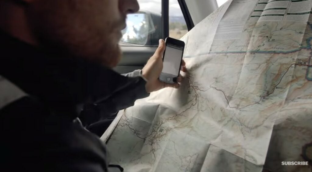 A young white man in a car with an open map in front of him