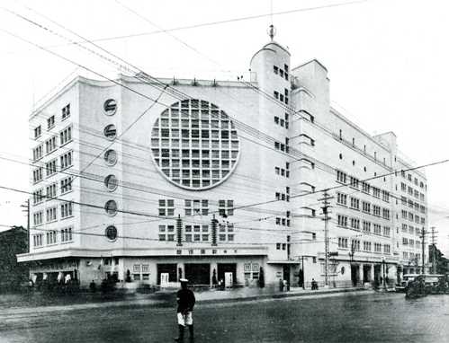 A black and white photograph of a striking building with a large, circular window at the front. It used to be Osaka's kabuki theatre from 1932 to 1958.