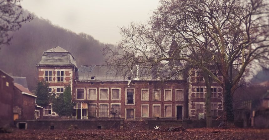 A long, two-story, brick manor house that has been abandoned for some time.