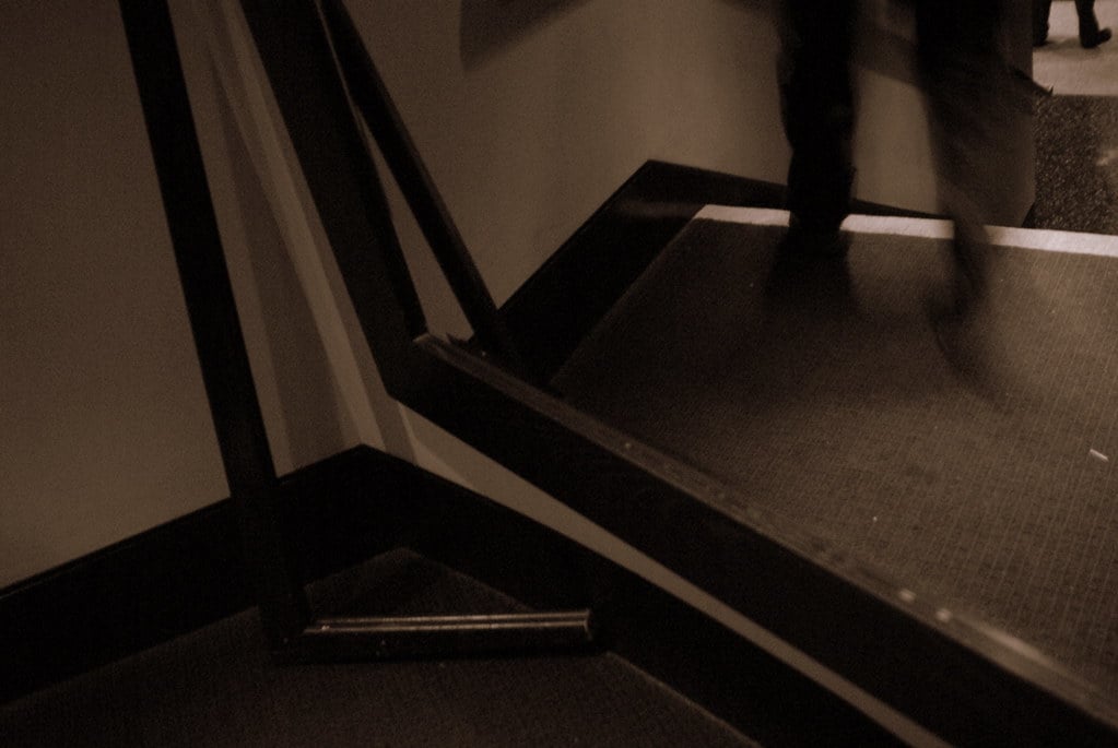 The corner of a room, with a broken mirror frame reflecting the floor back out at the rest of the room.