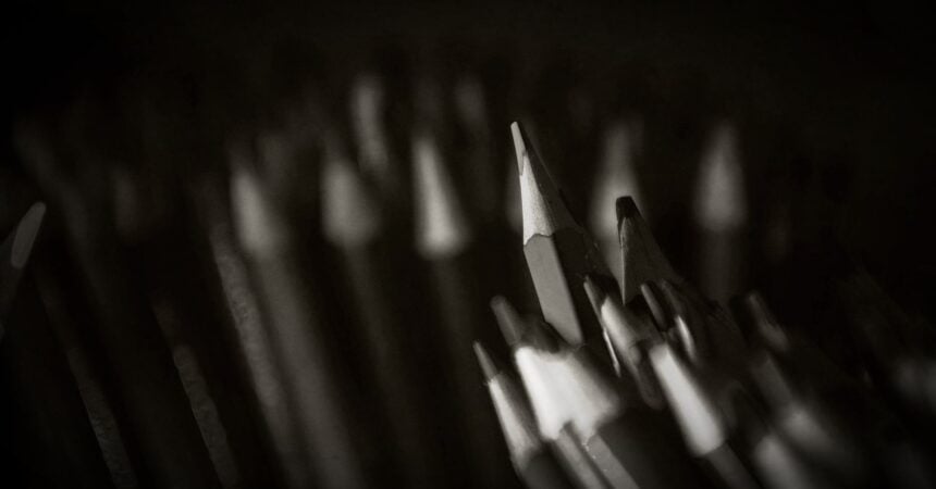 A black and white image of a large collection of wooden pencils, sharpened, standing up in bunches.