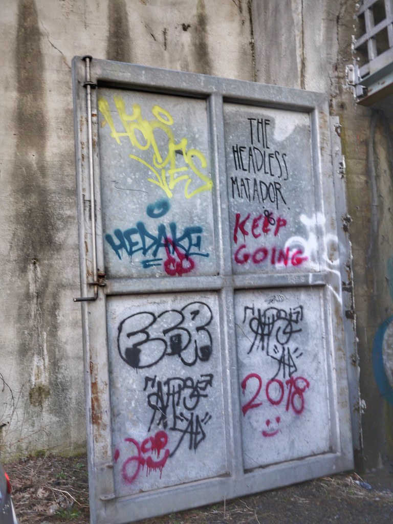 A large, four-paneled door in the abandoned Cincinnati Subway. It's covered in graffiti.