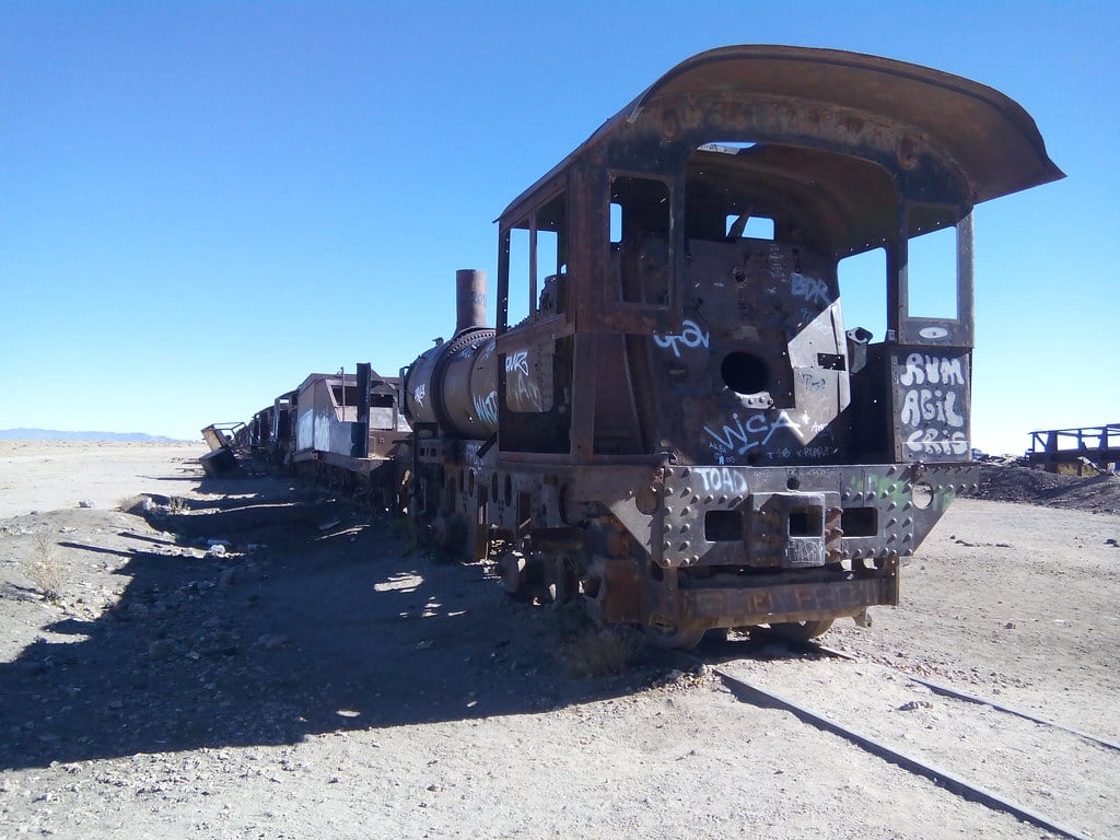 An abandoned train car against a blue sky in the desert.