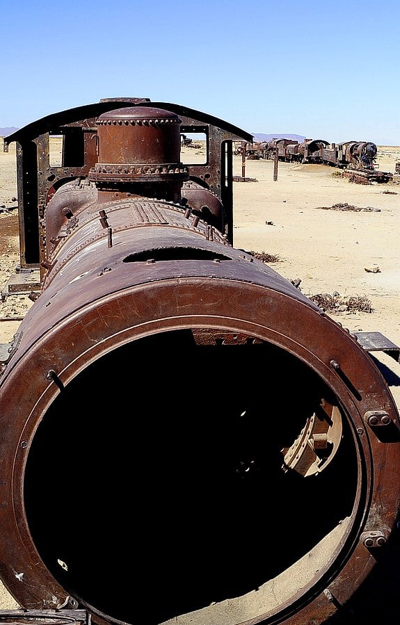 A view from the top of a rust-colored, abandoned train engine in the desert.