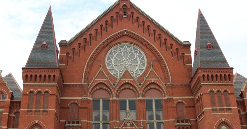 The exterior of Cincinnati Music Hall, a High Victorian Gothic building made of red brick with peaked gables and a beautiful rose window.