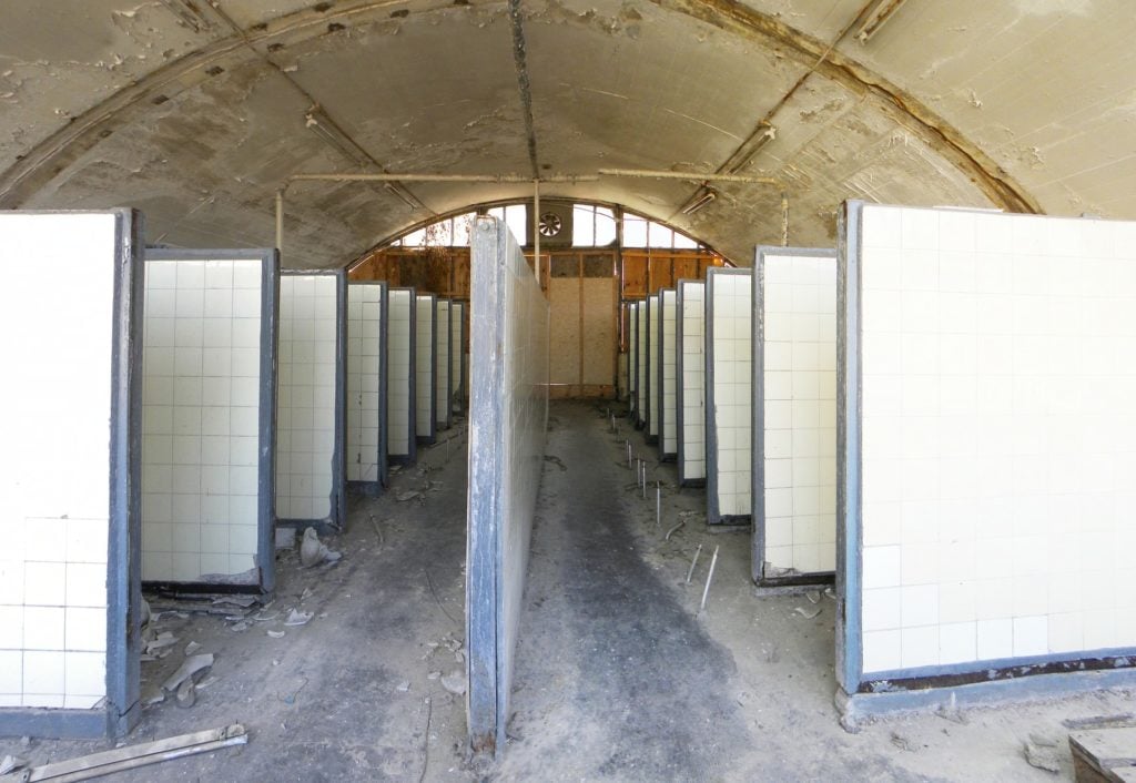 A row of cubicles in an abandoned public toilet.