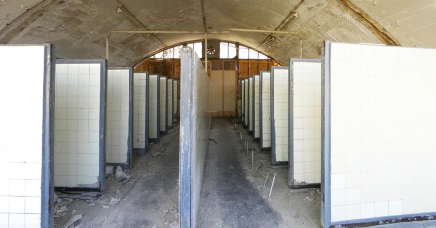 A row of cubicles in an abandoned public toilet.