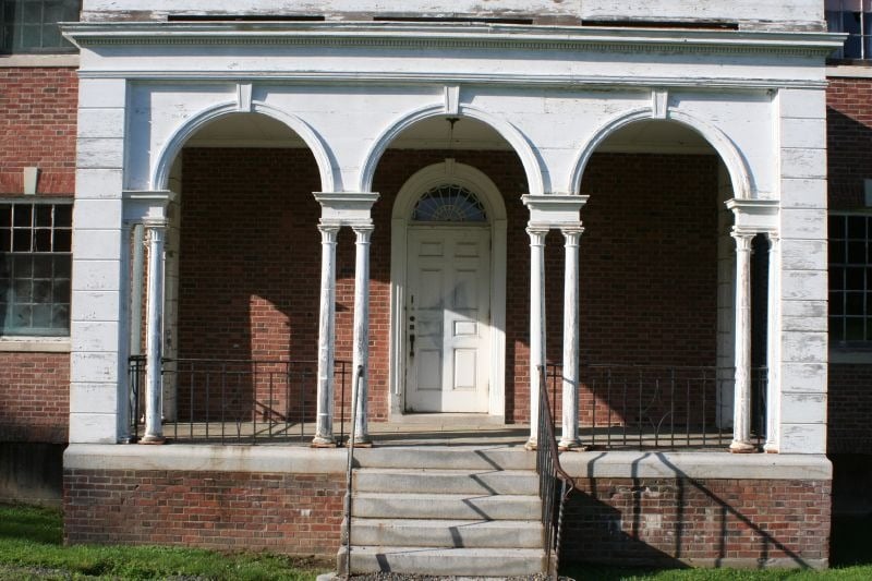 The front door of a brick building at Fairfield Hills, surrounded by white arches
