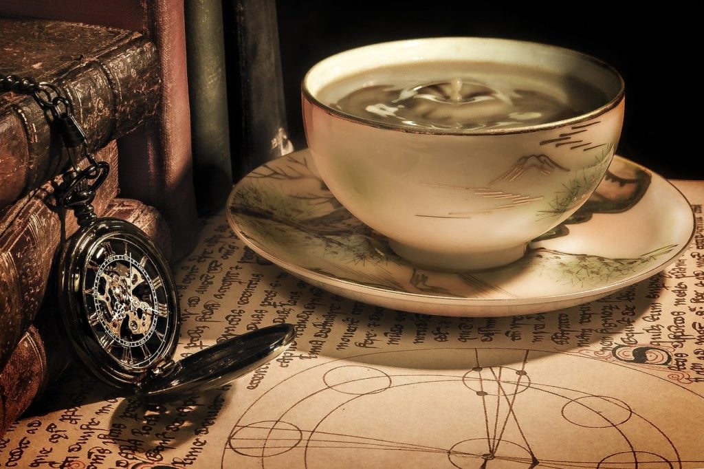 A tea cup with books and a pocket watch