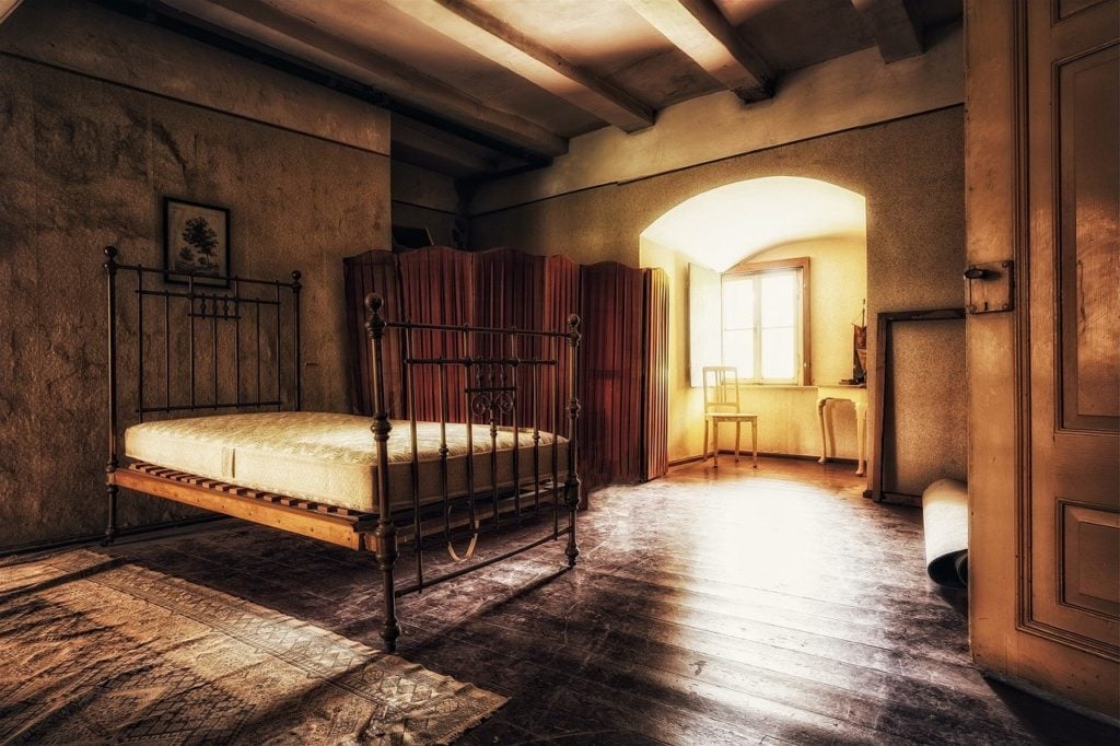 An old iron bedstead in an old, abandoned room