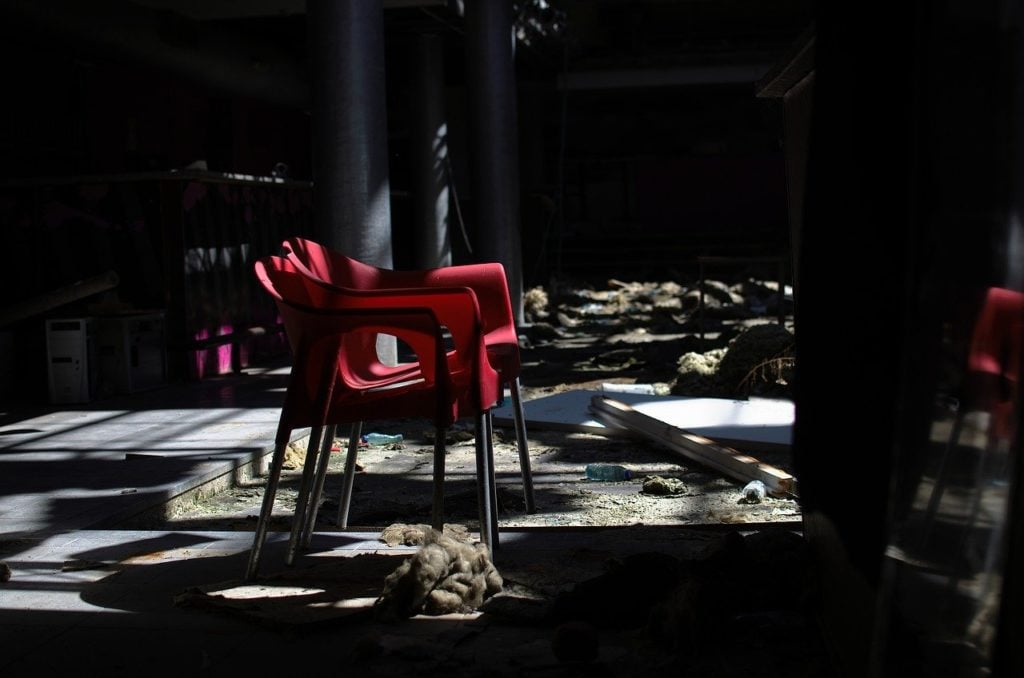 A red chair in a decaying, abandoned room