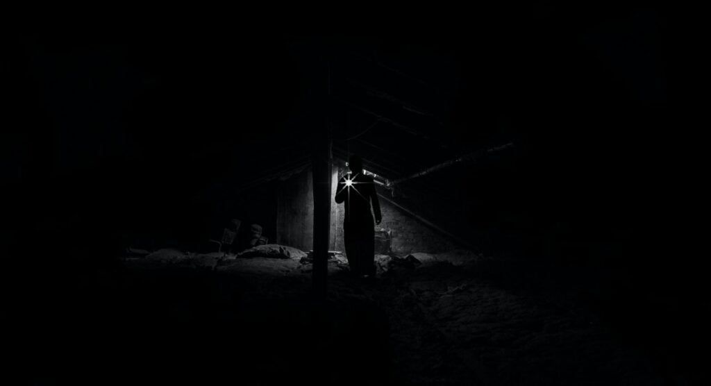 A human figure with a flashlight in a dark room