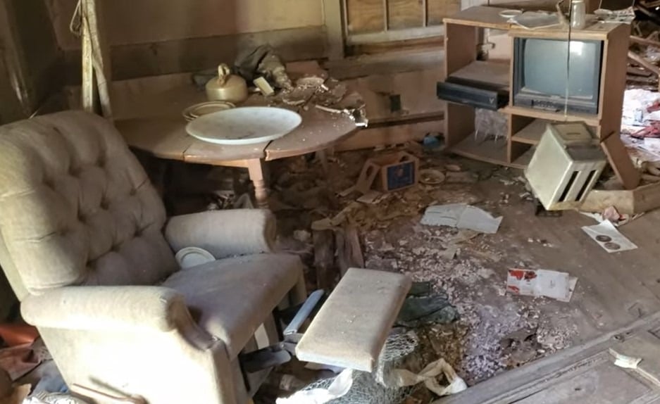 An armchair and other decaying furniture inside Winderbourne Mansion