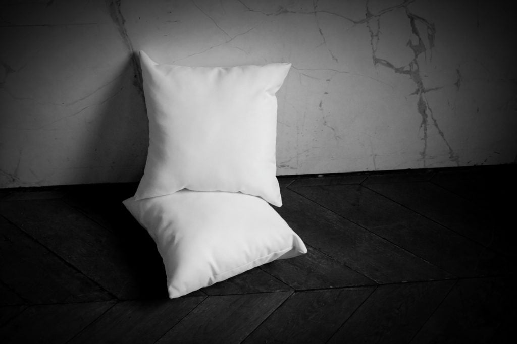 Two white pillows lying on a wood floor