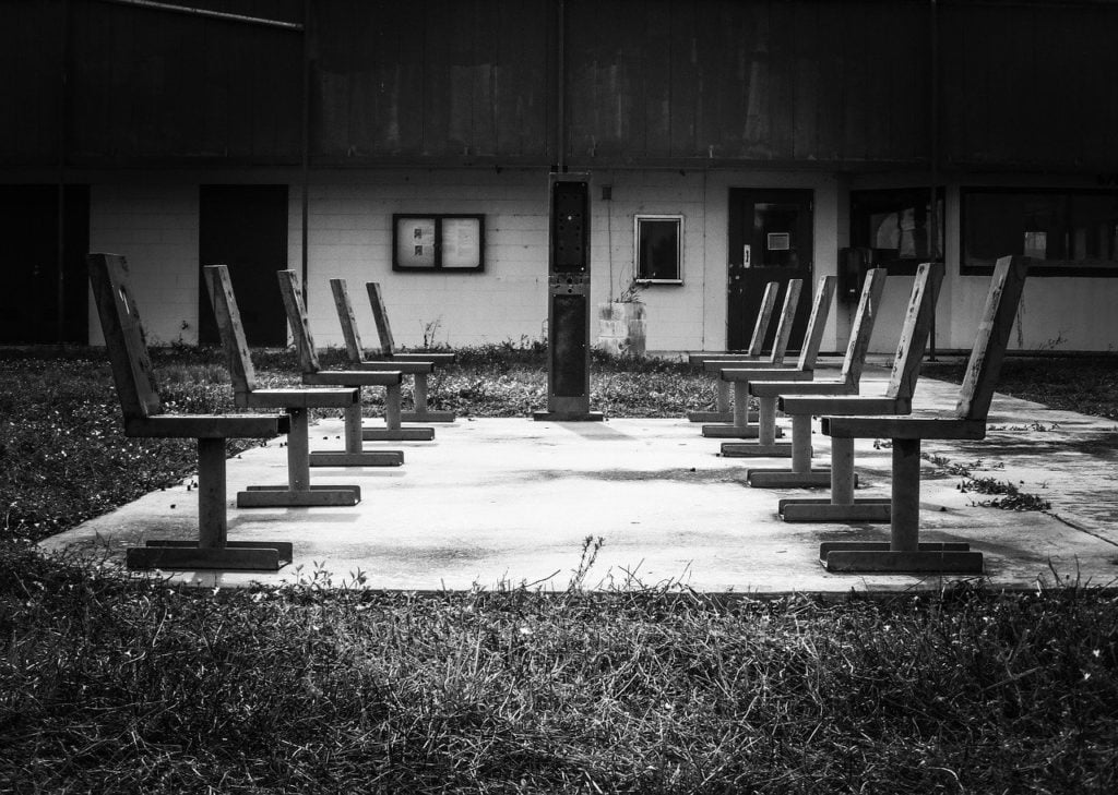 Two rows of empty chairs facing each other in an abandoned playground