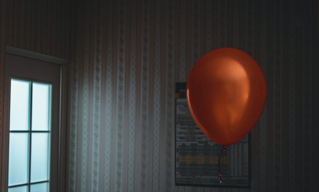 A red balloon floating alone in an abandoned room